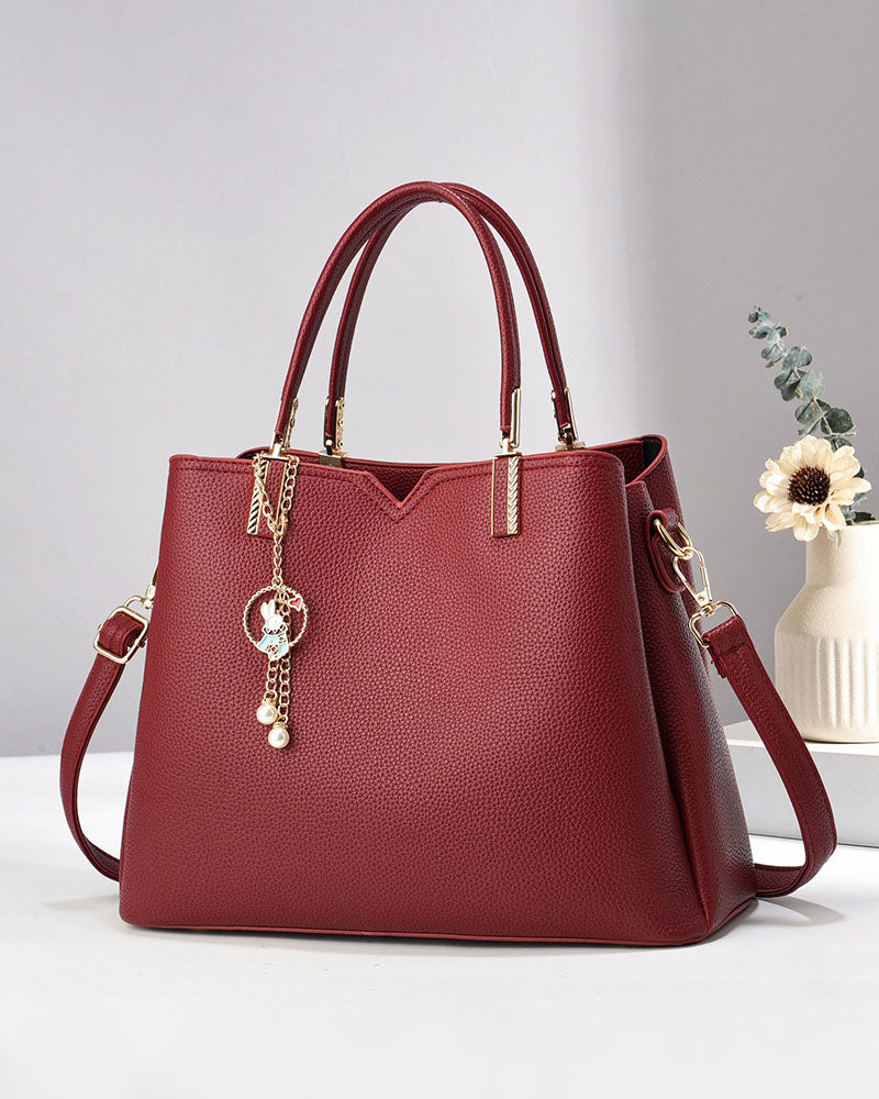 Bolso de mano y hombro con dije decorativo