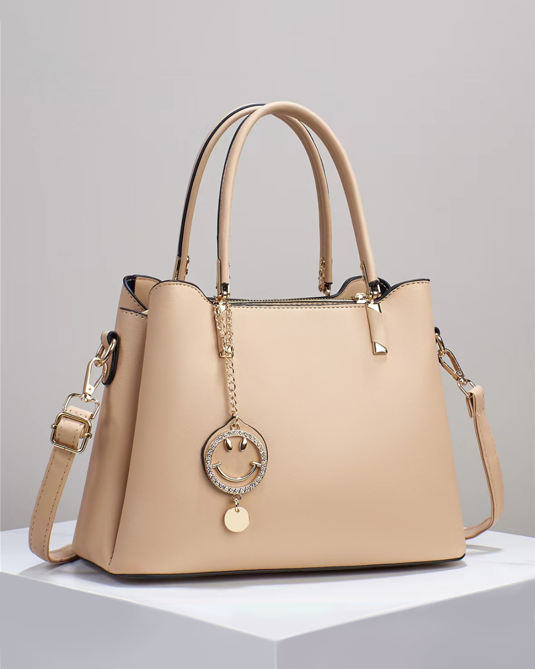 Bolso de mano con colgante sonriente. Detalles en dorado. Tiro para hombro