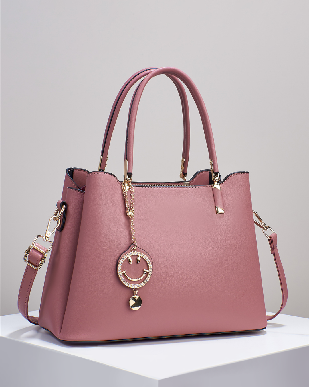 Bolso de mano con colgante sonriente. Detalles en dorado. Tiro para hombro