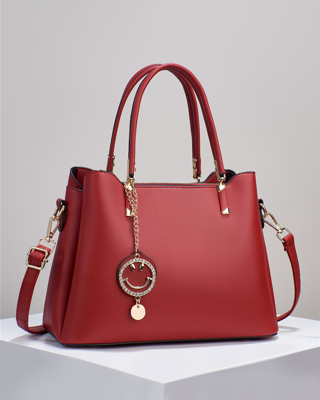 Bolso de mano con colgante sonriente. Detalles en dorado. Tiro para hombro