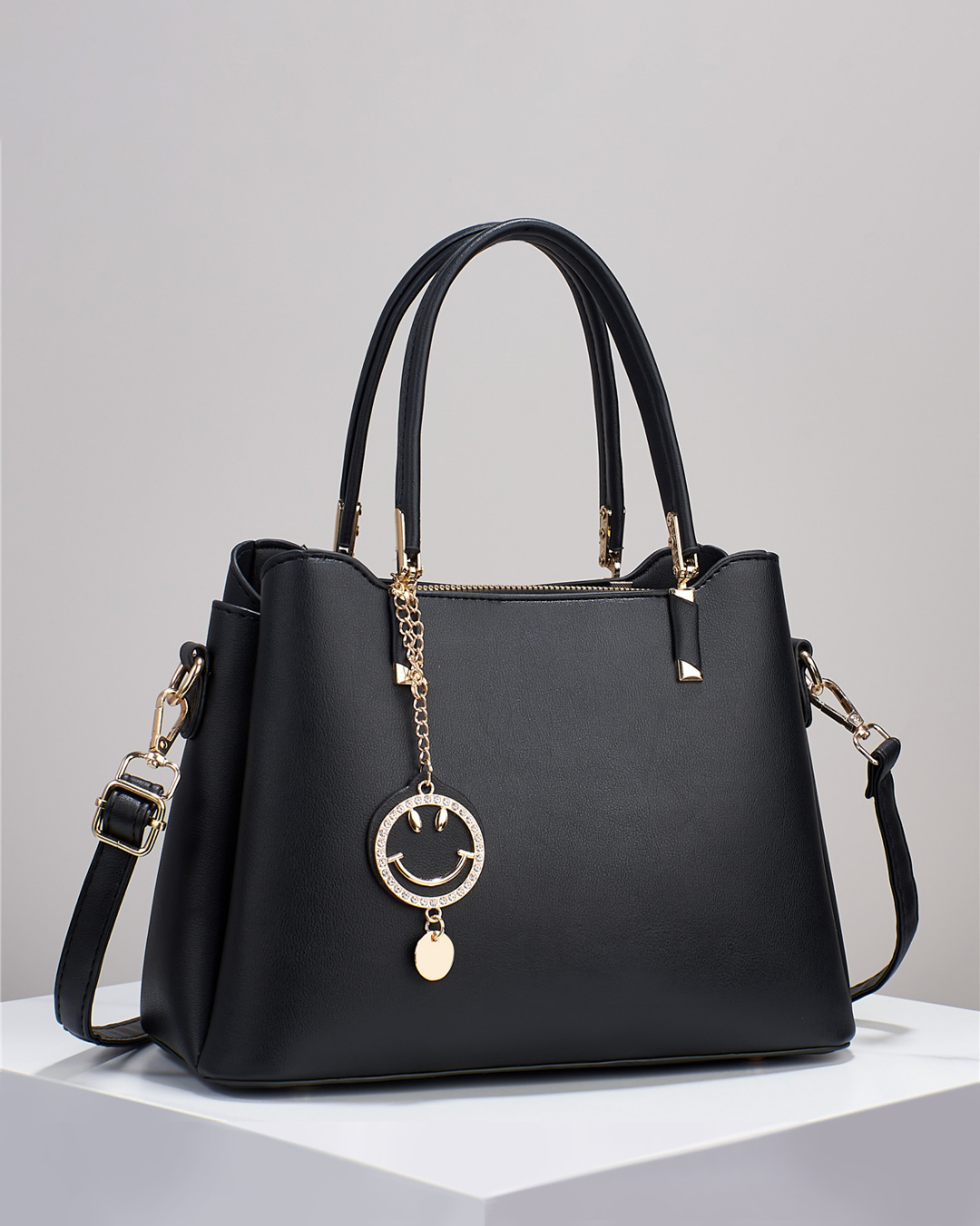 Bolso de mano con colgante sonriente. Detalles en dorado. Tiro para hombro