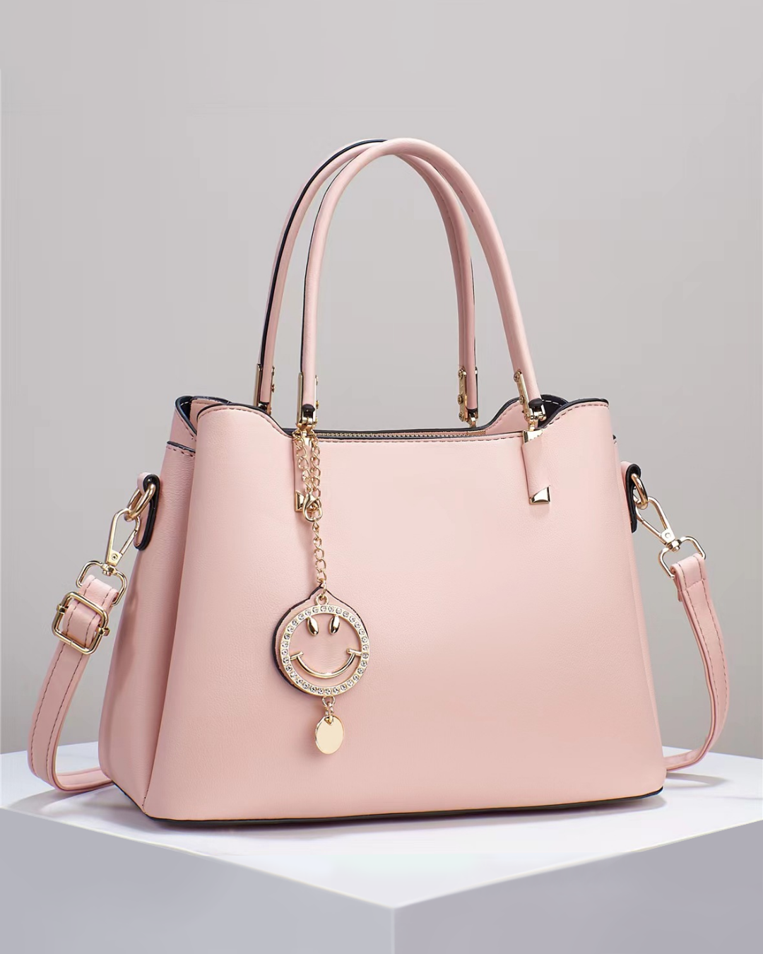 Bolso de mano con colgante sonriente. Detalles en dorado. Tiro para hombro