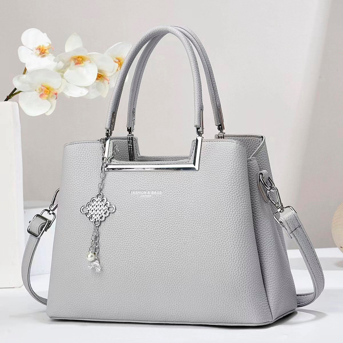 Bolso de mano con asas doble, correa de hombro desmontable. Dije decorativo plateado